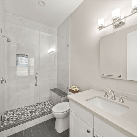 Guest bathroom with a marble-tiled shower and white vanity at The Ridge