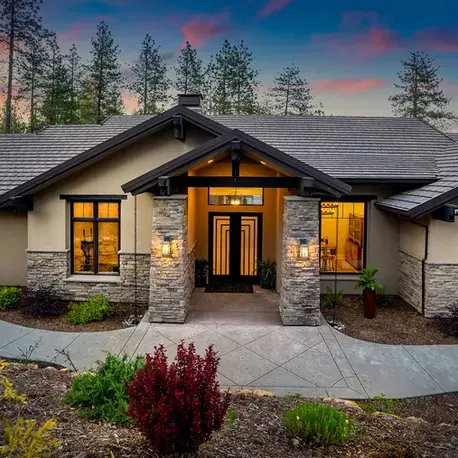 Front elevation lit at dusk with stone columns and a timber entry in Meadow Vista, CA