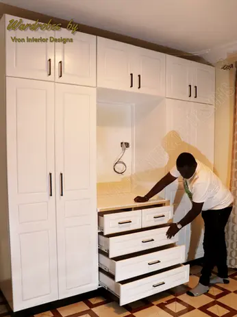 Four white door hinged wardrobe with a Tv section designed by vron interior designs.