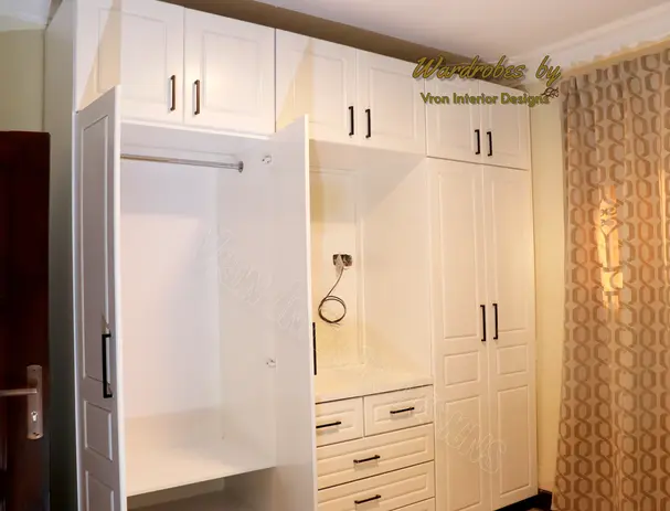 Four white door hinged wardrobe with Tv section and a closed in hanging section designed by vron interior designs