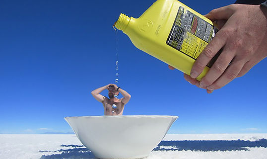 Foto de perspectiva creativa en el Salar de Uyuni donde una persona simula bañarse en el desierto de sal en Bolivia