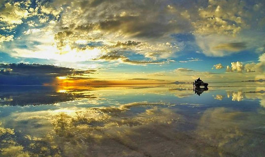 Atardecer en el Salar de Uyuni con vehículo turístico sobre el desierto de sal en Bolivia
