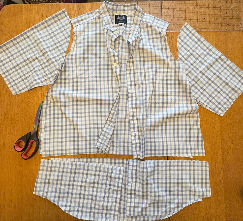 Cut blue and white checked shirt pieces laid out on a wooden table with scissors and a ruler, showing a sewing project in progress.