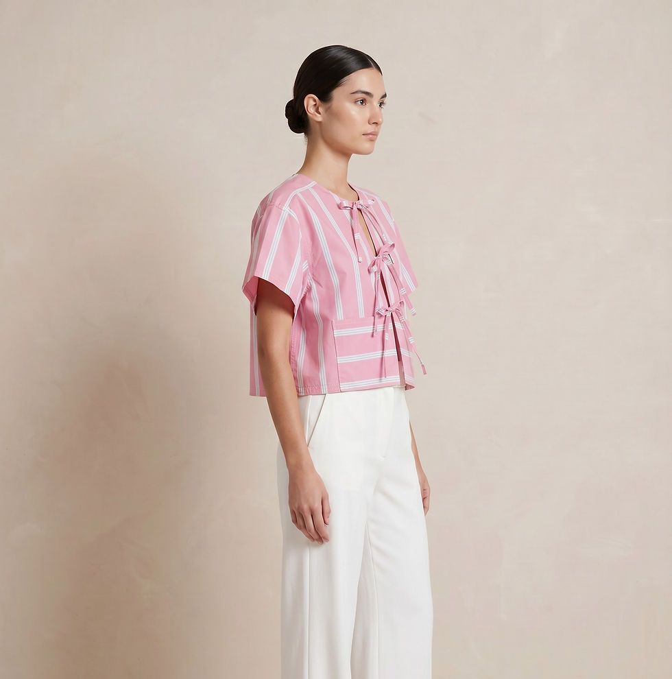 Side view of the candy‑stripe tie‑front blouse styled with high‑waisted white trousers and flat tan sandals.