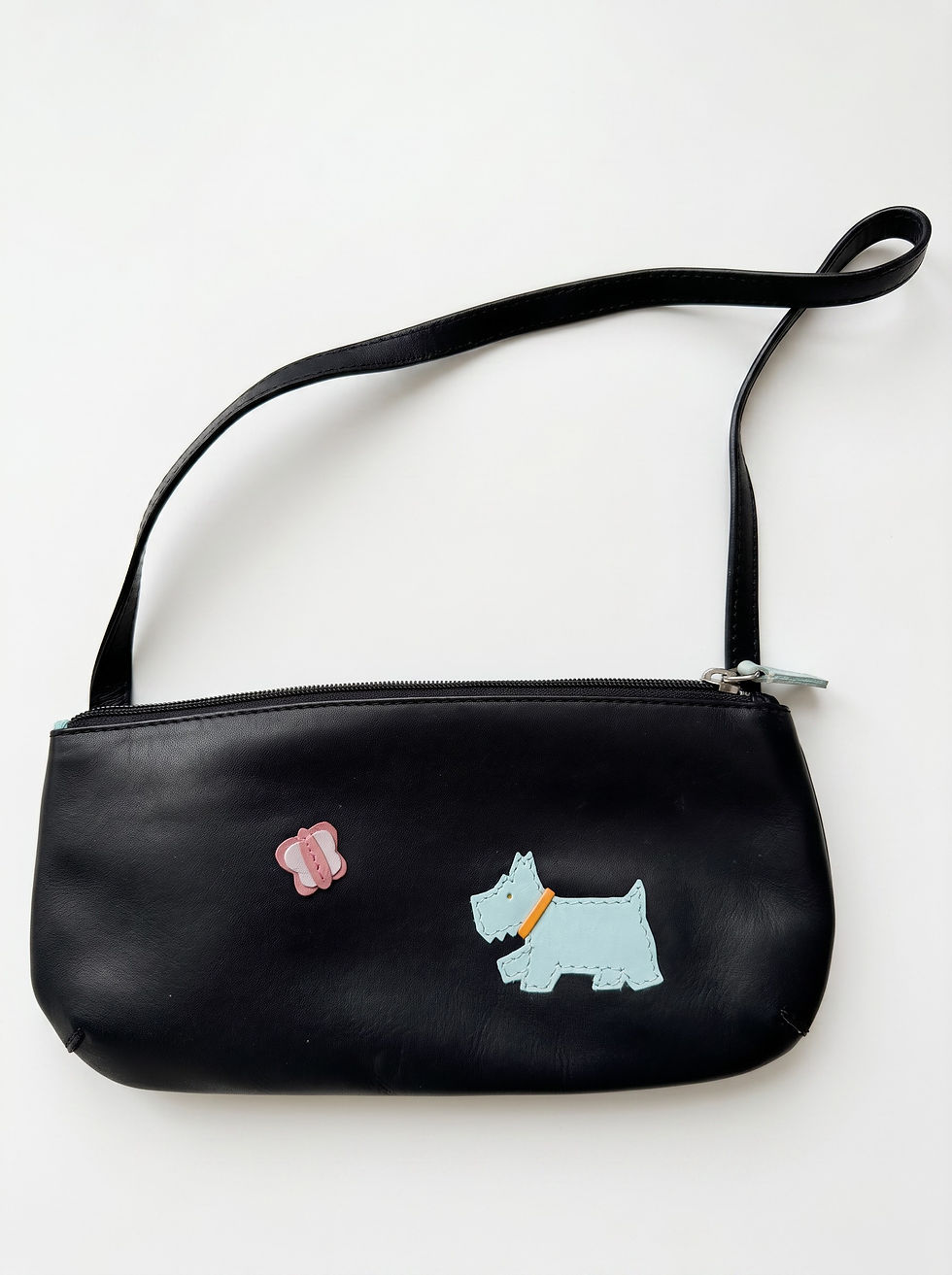 Small black leather shoulder bag with a blue Scottie dog appliqué and a pink butterfly on the front.
