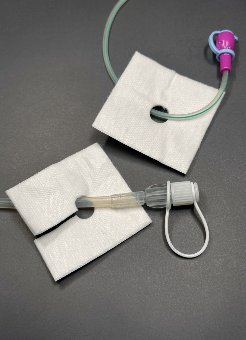 Two absorbent pads with enteral feeding tube and clip
