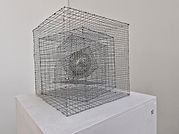The image contains a sculpture of a series of wire cages, containing an inner light.
