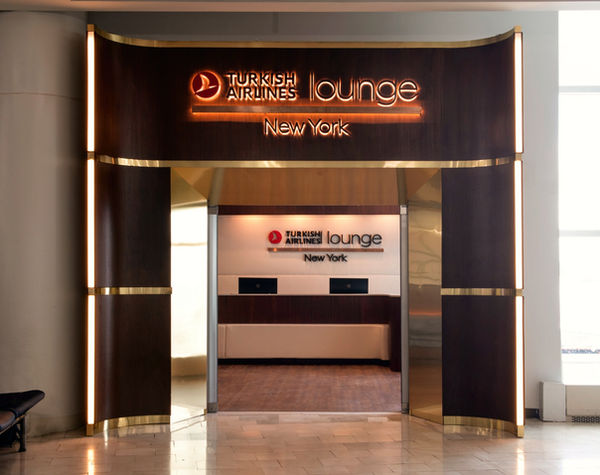 Interior of Turkish Airlines Lounge at JFK with warm walnut paneling and brass details.