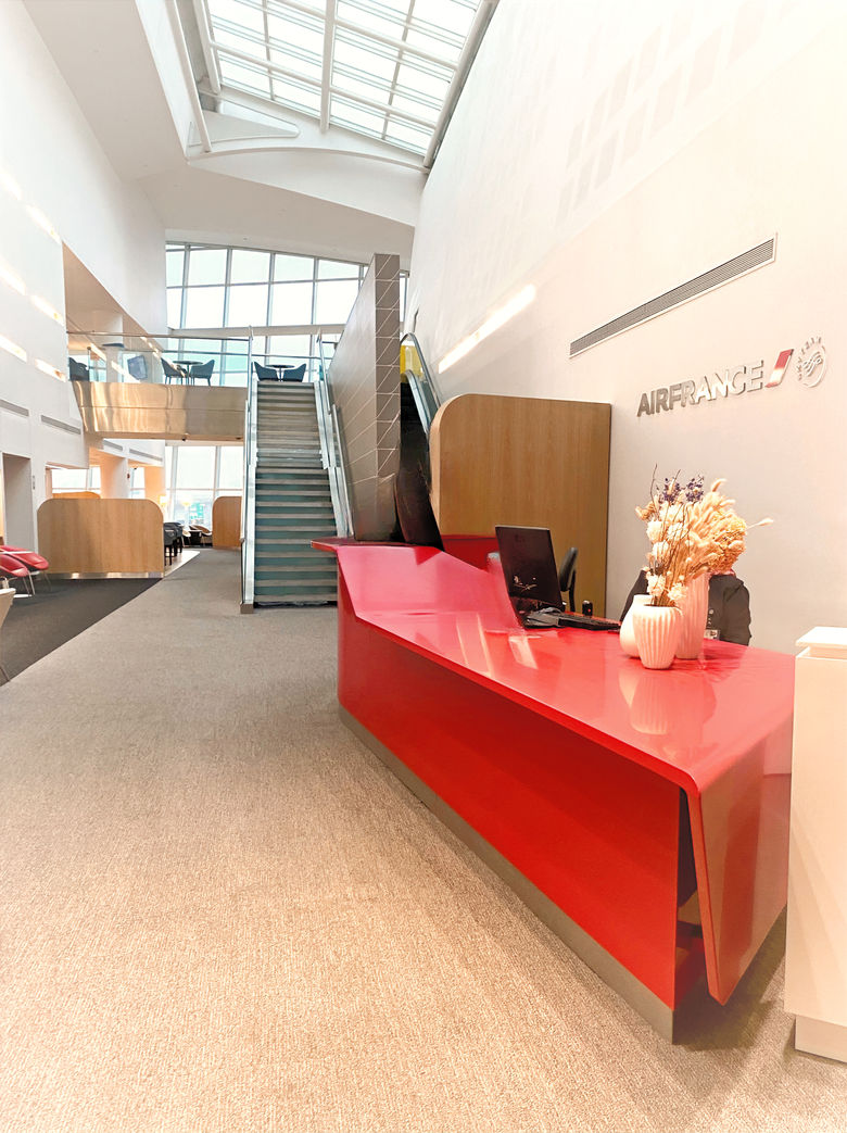 Airport lounge bar area with modern red counter and high ceilings.