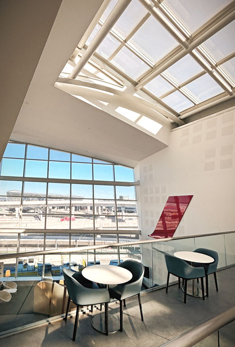 Contemporary airport lounge seating beneath a large sloped glass skylight.