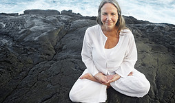 Older woman in lotus pose by the sea