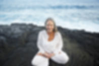 Older woman in lotus pose by the sea