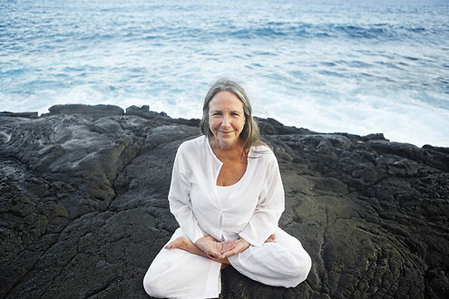 Older woman in lotus pose by the sea