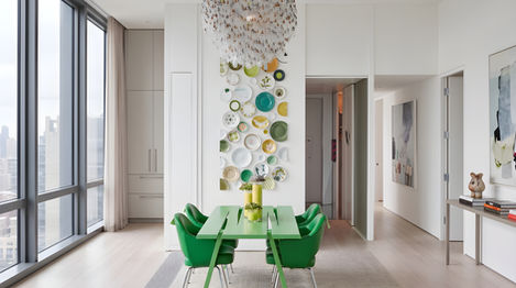 Wide-plank bleached Quartersawn Northern Hard Maple floors in a penthouse dining room with a green table and chairs, a decorative plate wall installation, a cascading chandelier, and floor-to-ceiling city views, installed by I.J. Peiser's Sons.