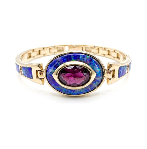 A red tourmaline is inset in malachite azurite with a gold border. 