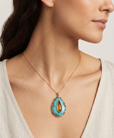 A golden tourmaline is inset into turquoise with a 14kt yellow gold border. 