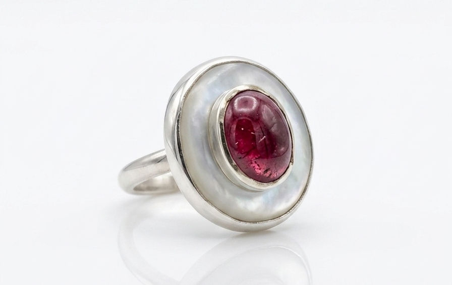 Red tourmaline is set on top of a pearl shell in silver.