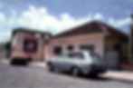 Casa antiga com o logo antigo da Autotravi na parede e 02 carros antigos estacionados em frente