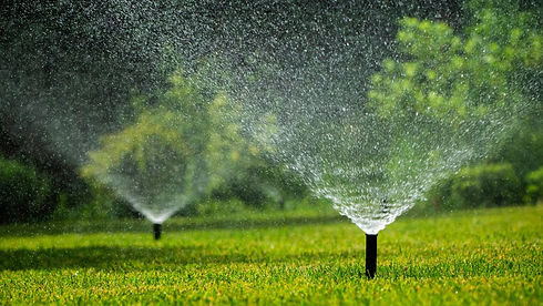 Sprinkler system irrigating a green lawn with a fine mist of water..jpg