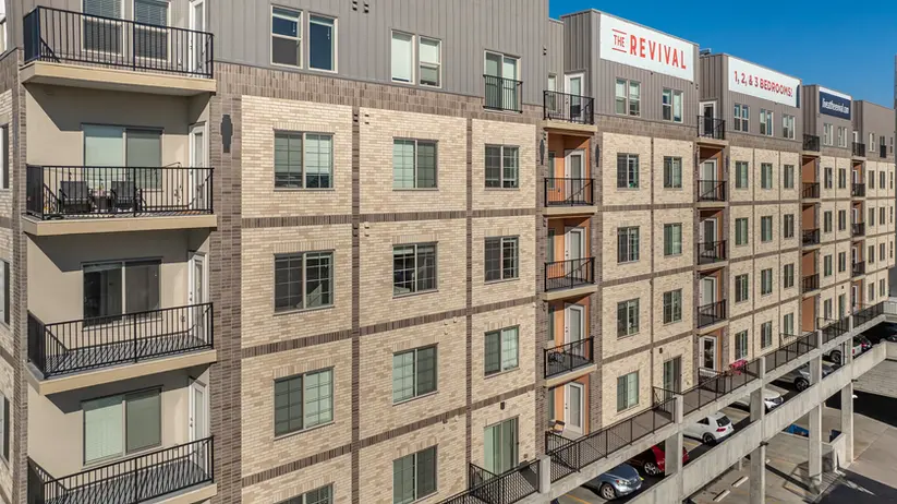 Multi-story residential building showcasing Roman Theatre, Desert Land, and Manganese brickwork with stacked balconies and metal railings