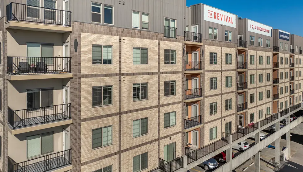 Residential building exterior with Roman Theatre, Desert Land, and Manganese brick facade, repeating window grid, and recessed balconies