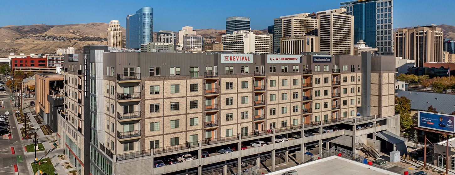 The Revival Apartments in Salt Lake City, Utah show off the Desert Land, Roman Theatre, and Black Beauty thin brick on it's exterior with the mountains on the horizon. This is an angled view further away from the building.