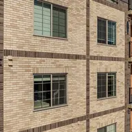 Contemporary apartment block using Roman Theatre, Desert Land, and Manganese brick colors with balcony corridors and parking level below
