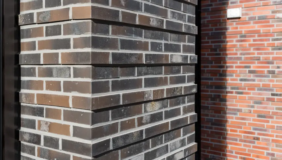 Ground-level view of the hotel entrance clad in Old Fort thin brick in King Size, featuring a covered drive-through and recessed lighting.
