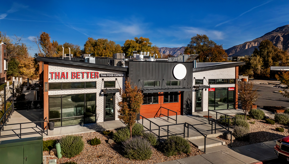 Thai Better and Taco Regio's in Ogden, Utah has a light facade with white wash matte thin brick to blend in the the desert heat of Utah. This is a full view with Thai Better corner with mountain in background.