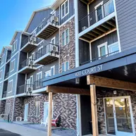 Front entry view of a multi-story apartment building with Blend of 4 thin brick in varied earth tones, black metal balconies, and a covered entrance