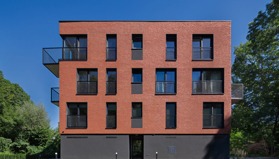 Symmetrical front view of apartment building finished in Bengali Sunrise thin brick in king size, with evenly spaced windows, balconies, and minimalist landscaping.