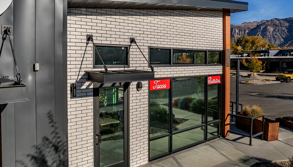 Thai Better and Taco Regio's in Ogden, Utah has a light facade with white wash matte thin brick to blend in the the desert heat of Utah. This is an upclose view from parking lot.