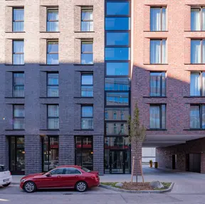 Street-level perspective of the Holiday Inn in Germany finished in Old Fort thin brick in King Size, with trees, parked cars, and clean urban streetscape.