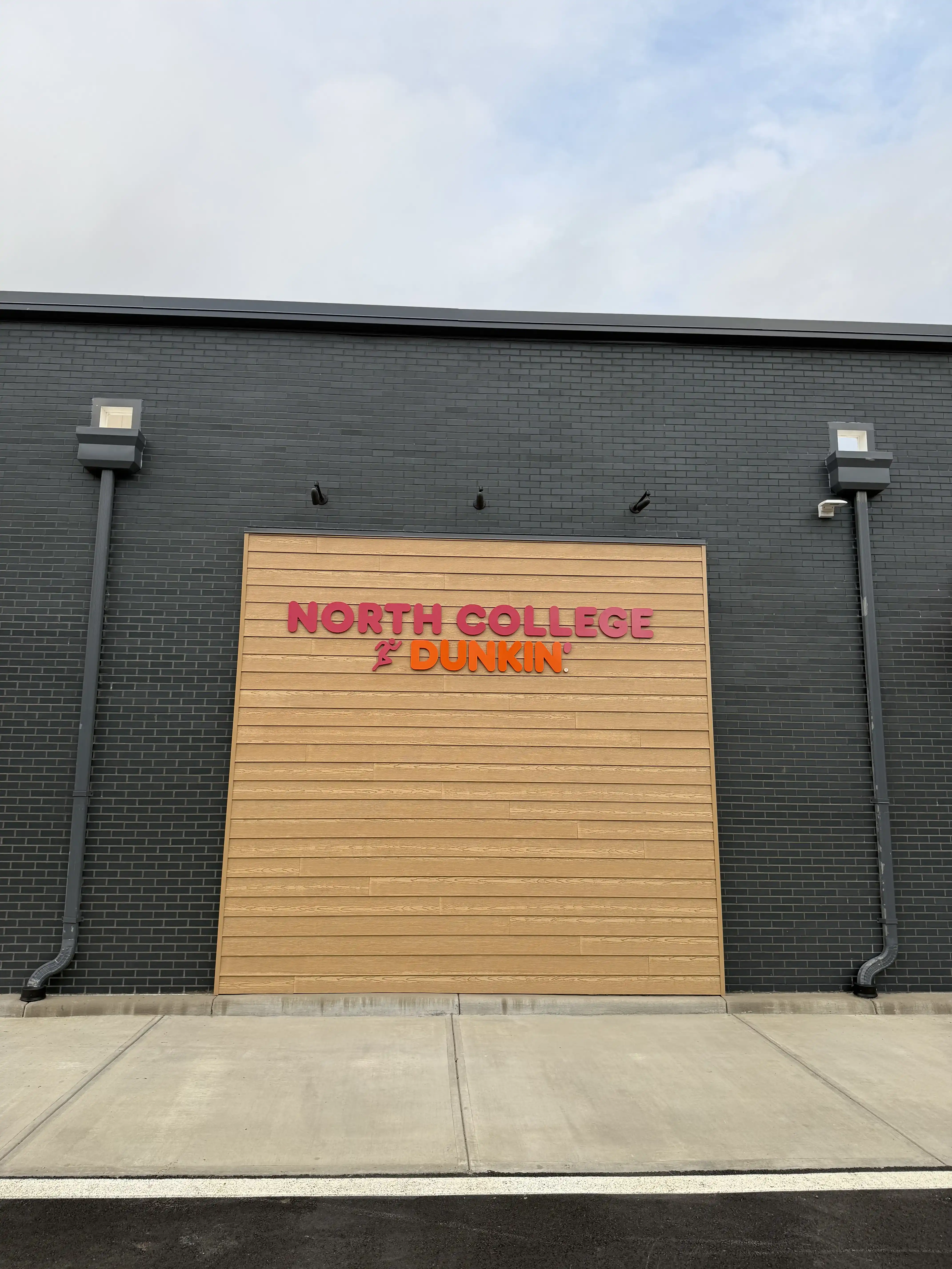 Manganese thin brick pairs with wood accents for a clean retail façade.
