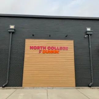 Manganese thin brick pairs with wood accents for a clean retail façade.