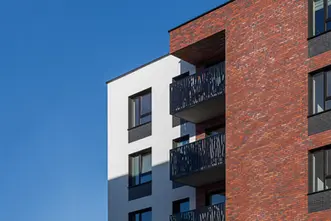 Close-up of apartment balconies against a red brick façade constructed with thin brick blend Red Square, Heart Brick, and Gothic Smile, King 3/8" size, highlighting varied red hues and textured dark accents.