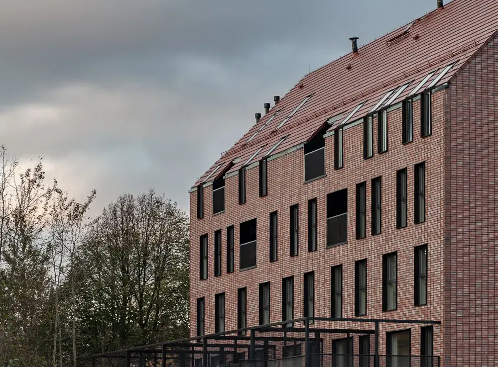Contemporary multi-family housing with Wall Street thin brick in King size, showing rhythmic vertical windows and black steel balcony structures against autumn landscaping.
