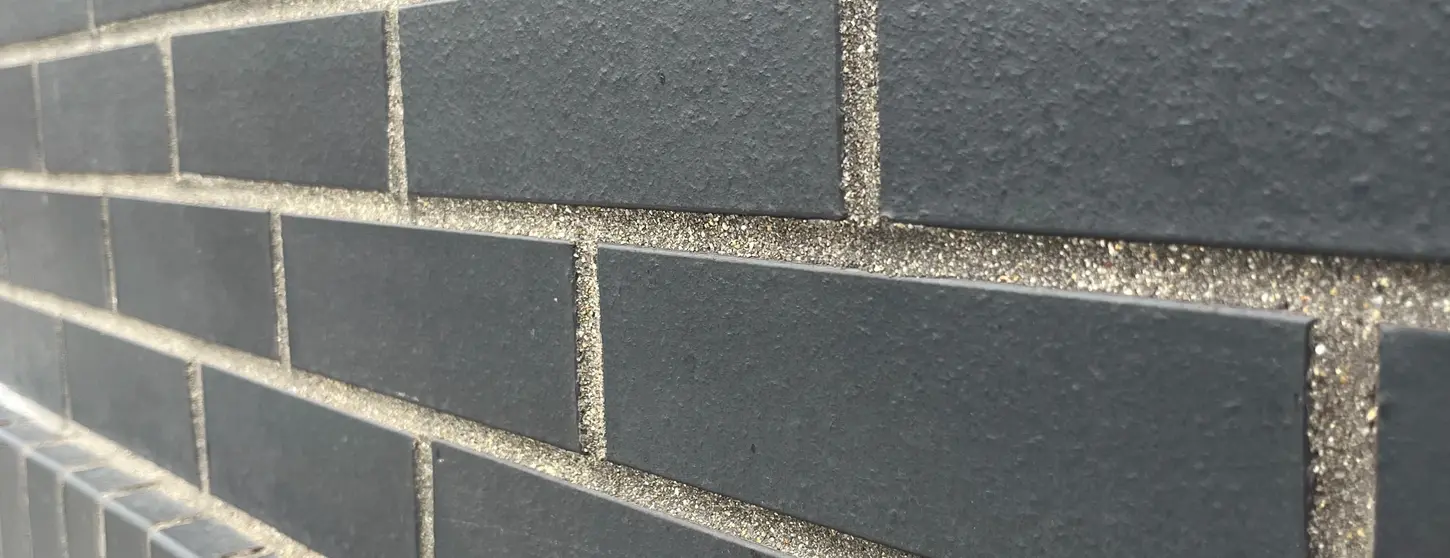 Close-up of Manganese Modular thin brick at 10 Taber Street, showing its dark gray color, subtle texture and vertical detailing.
