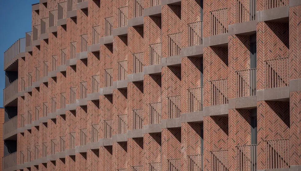 Custom red thin brick creates a repeating geometric pattern across the balconies of Bernardyńska 4 in Wrocław.