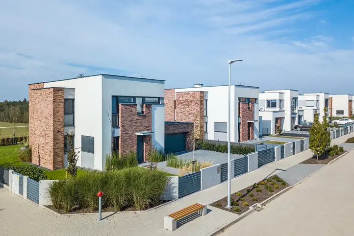 Modern single-family homes with Brick Street thin brick in modular size on the façade, featuring white stucco volumes, landscaped front yards, and a contemporary residential street setting.