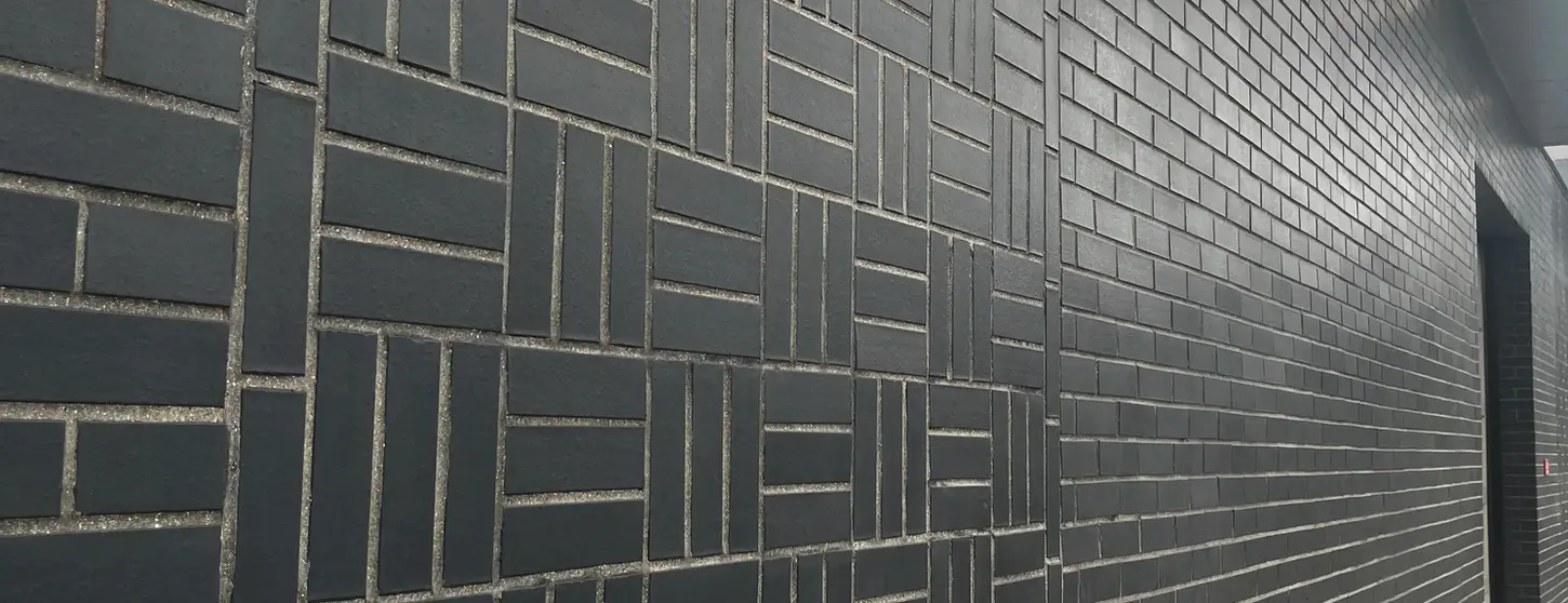 Manganese Modular thin brick arranged in a decorative geometric pattern along a modern interior corridor in New York.