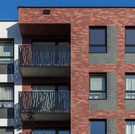 Apartment façade with modern black metal balcony railings set against thin brick blend Red Square, Heart Brick, and Gothic Smile, King 3/8" size, displaying a balanced mix of vibrant red tones and moody dark highlights.