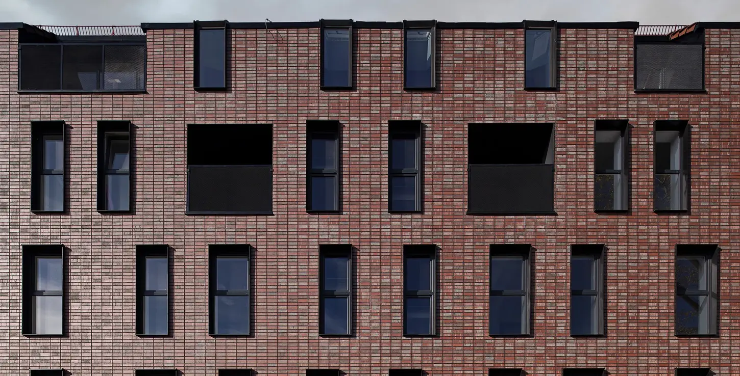 Detailed façade view of Wall Street thin brick in King size, showcasing subtle color variation and grid-like brick pattern framed by dark window trim.