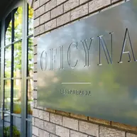 Close-up of the Oficyna Restaurant signage mounted on an Aztec Ghost thin brick wall, showing the brick’s muted beige-gray color palette and handcrafted texture.