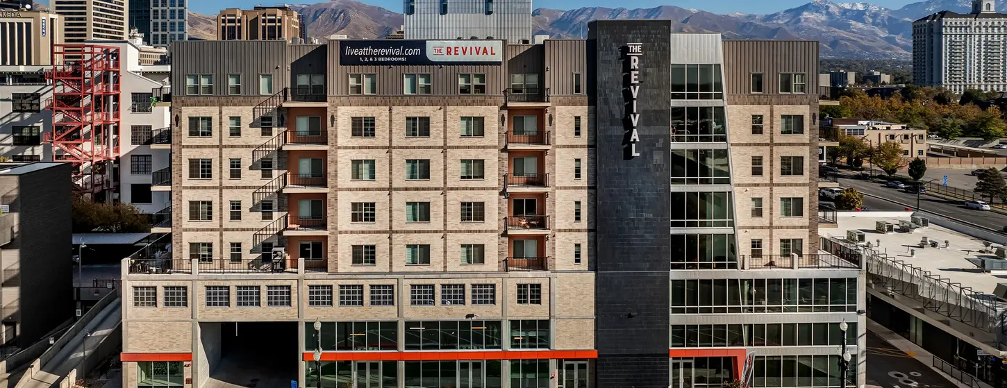 Mixed-use residential building featuring thin brick in Roman Theatre and Desert Land with Manganese accents, set against a downtown skyline and mountain backdrop.