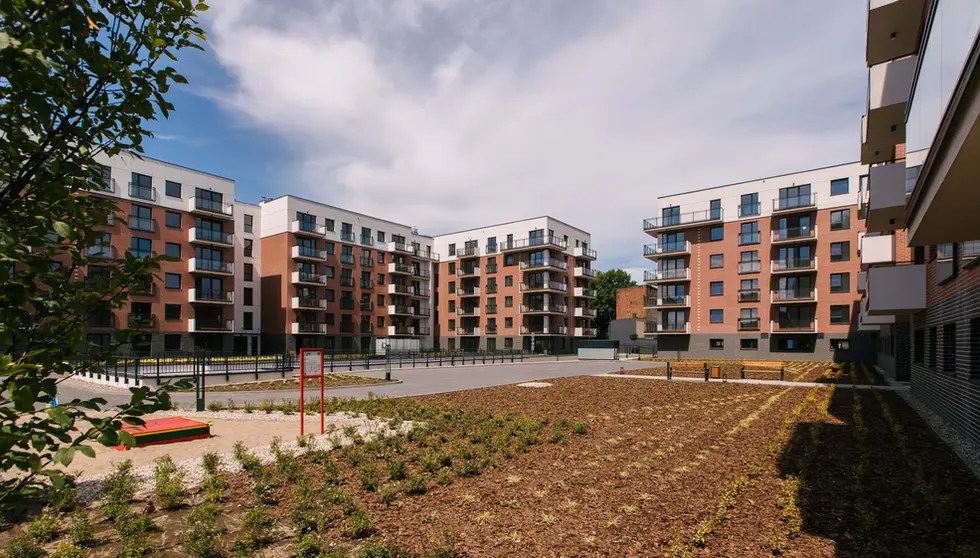 Courtyard view of the Nowa Grobla apartment community, featuring Ruby Red and Black Stone thin brick across several buildings.