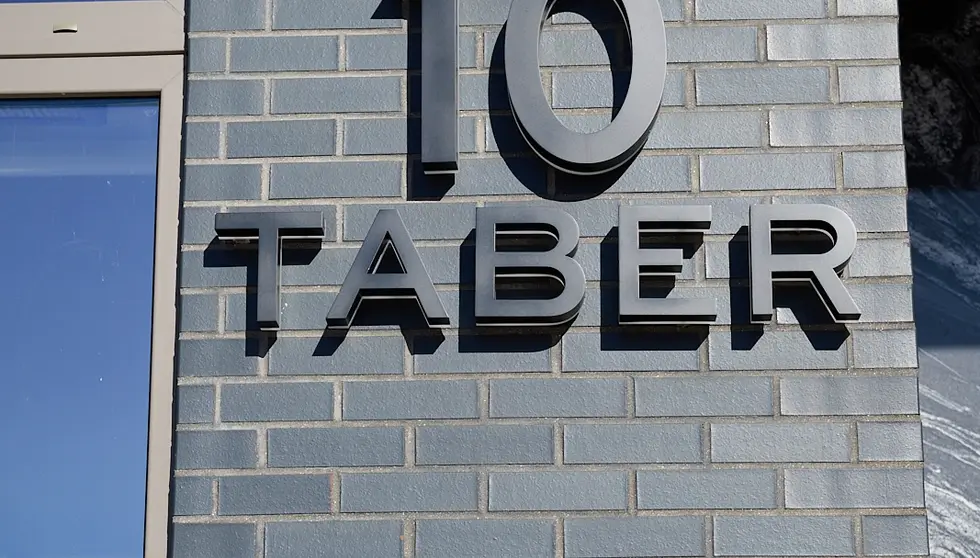The 10 Taber building sign mounted on a facade of dark gray Manganese thin brick in Modular size in Boston.