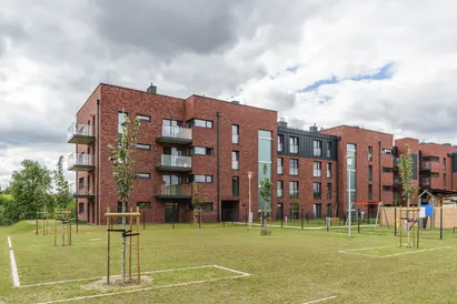 Contemporary residential façade featuring Gothic Smile thin brick in king size, with glass balconies, vertical window panels, and landscaped lawn in the foreground.