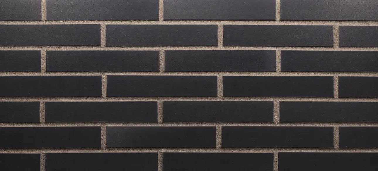Manganese Norman size thin brick veneer with deep charcoal-black bricks and a smooth matte finish in a horizontal running bond