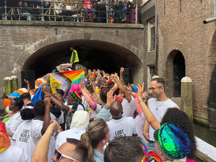 Deelnemers aan Pride Utrecht varen onder een brug door.